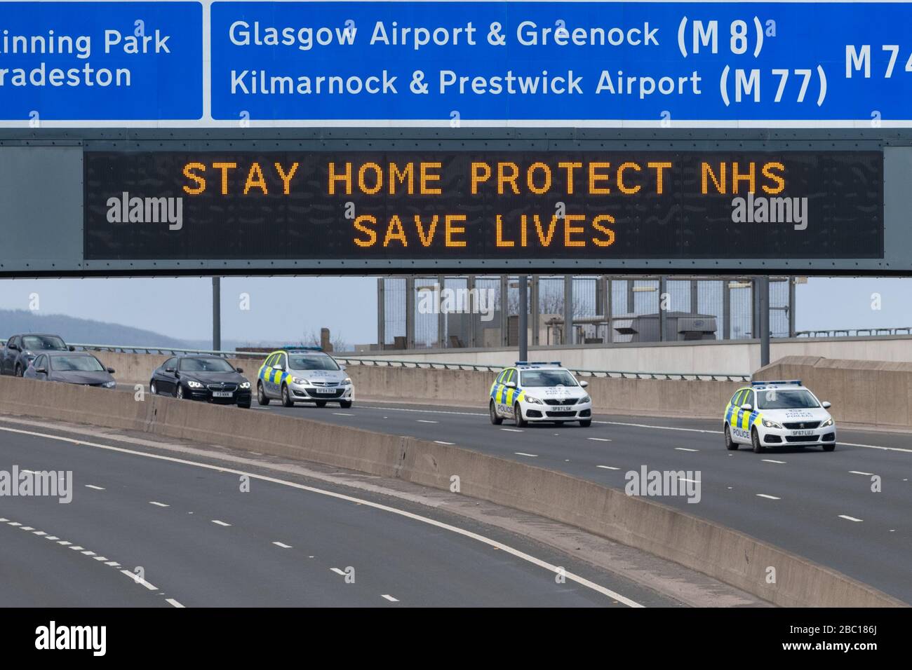 Glasgow, Scozia, Regno Unito. 2nd Apr, 2020. Veicoli della polizia che passano sotto 'Stay Home Protect NHS Save Lives' Sign in Glasgow Credit: Kay Roxby/Alamy Live News Foto Stock