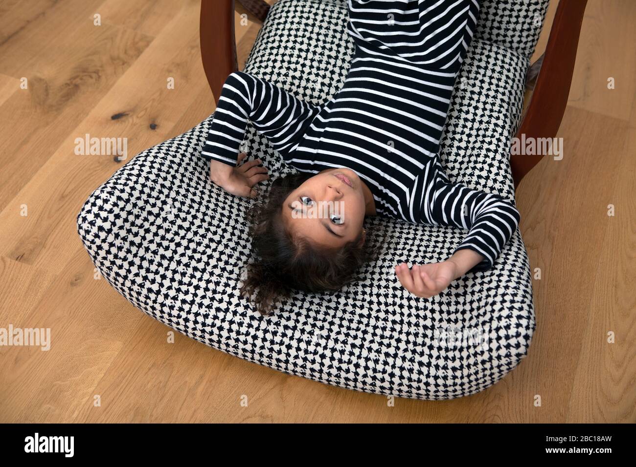 Ritratto di bambina sdraiata al di sopra della poltrona Foto Stock