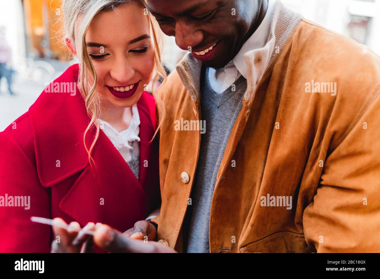 Sorridente giovane coppia che condivide il cellulare Foto Stock