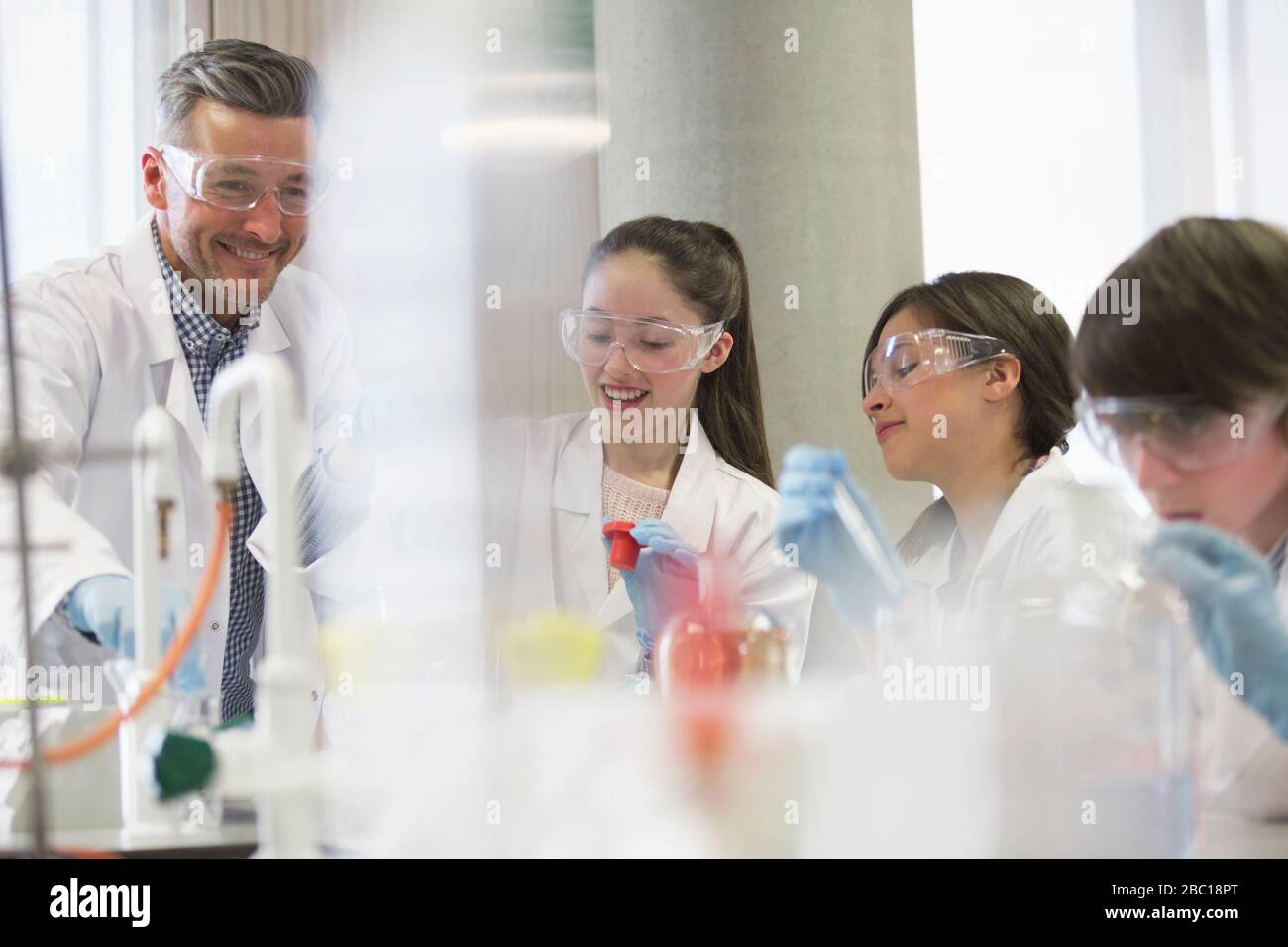 Insegnante di sesso maschile e studenti che conducono esperimenti scientifici in classe di laboratorio Foto Stock