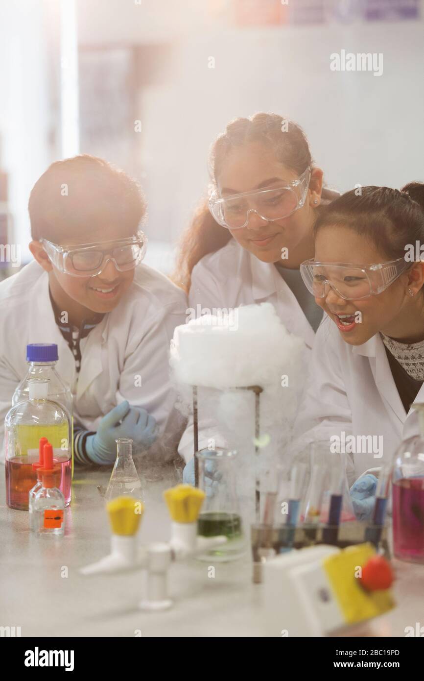 Sorpresi gli studenti che conducono esperimenti scientifici, osservano la reazione chimica in laboratorio in classe Foto Stock