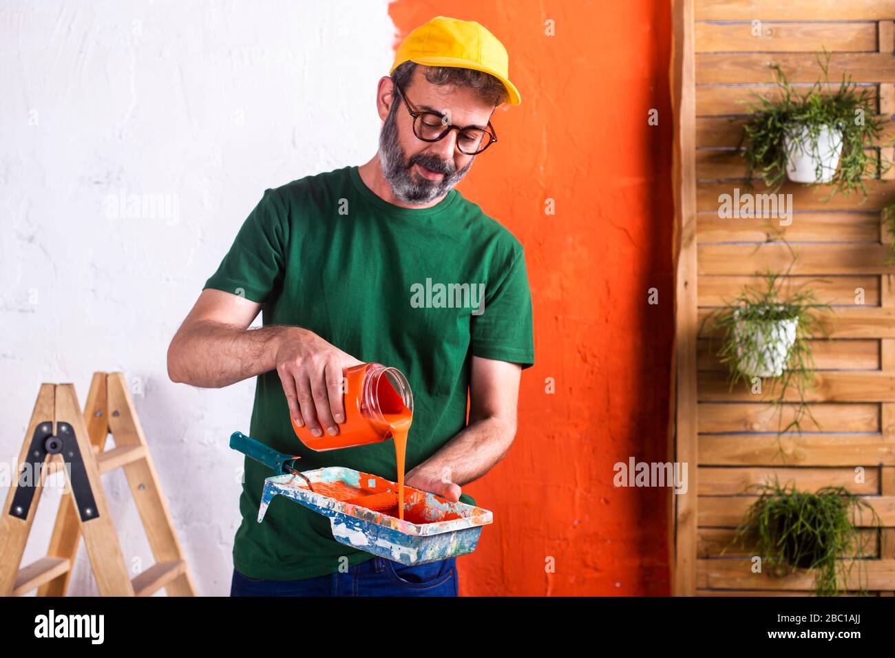 Uomo che versa vernice arancione nel vassoio di vernice Foto Stock