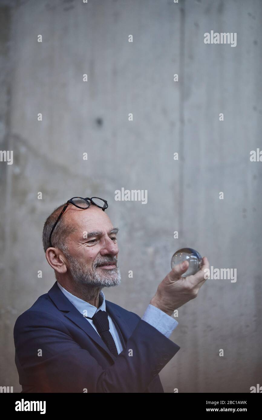 Uomo d'affari senior che guarda la palla di cristallo Foto Stock
