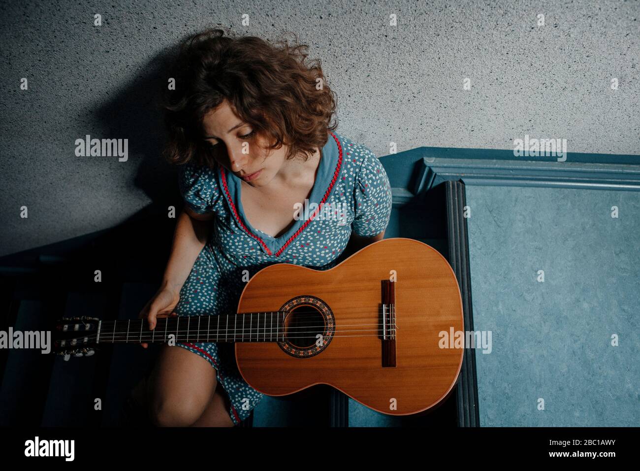 Triste giovane donna seduta sulle scale con la chitarra Foto Stock