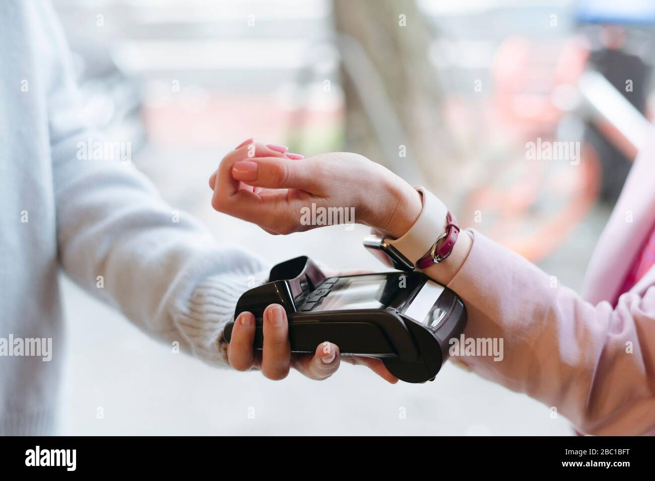 Mano di donna, pagando senza contanti al terminale POS con il suo smartwatch Foto Stock