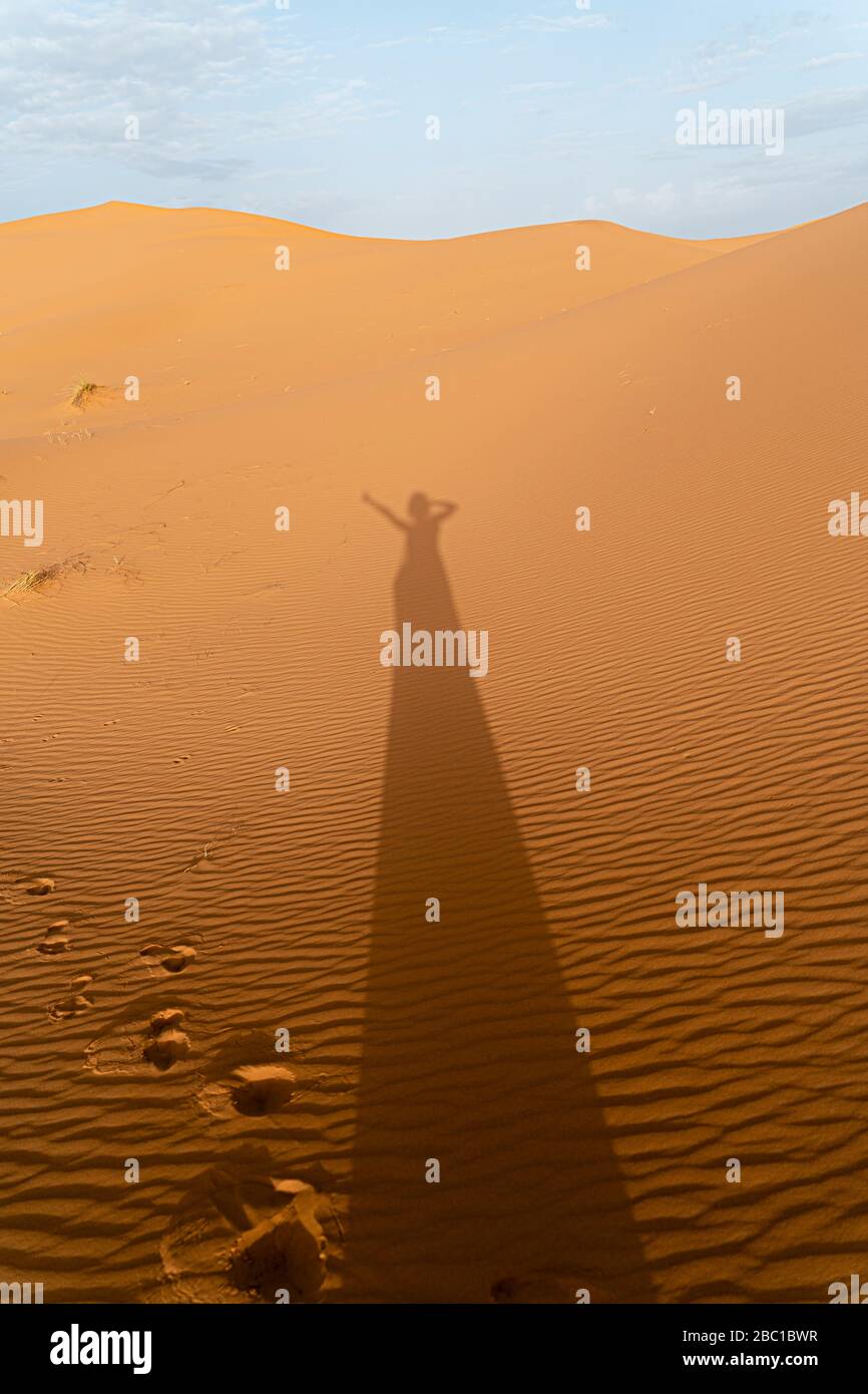 Ombra di una donna sulle dune di sabbia nel deserto del Sahara, Merzouga, Marocco Foto Stock