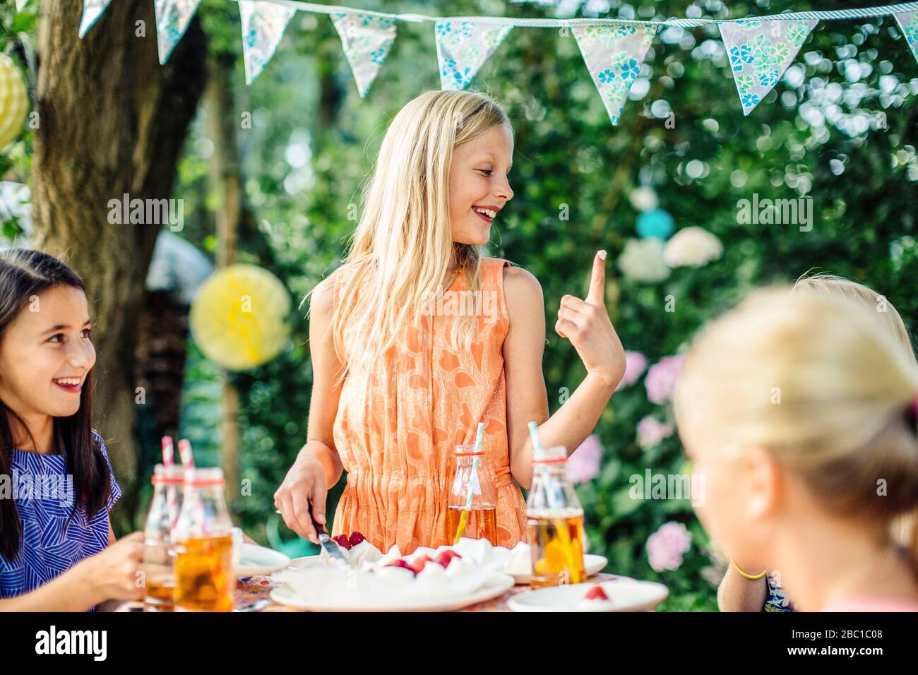 Ragazza che si tuffa in torta su una festa di compleanno all'aperto Foto Stock