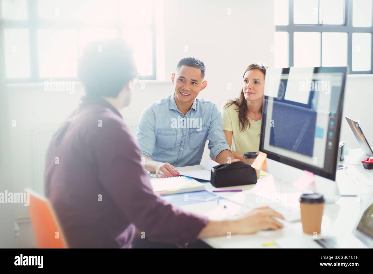 Progettisti che parlano, lavorando al computer in ufficio Foto Stock