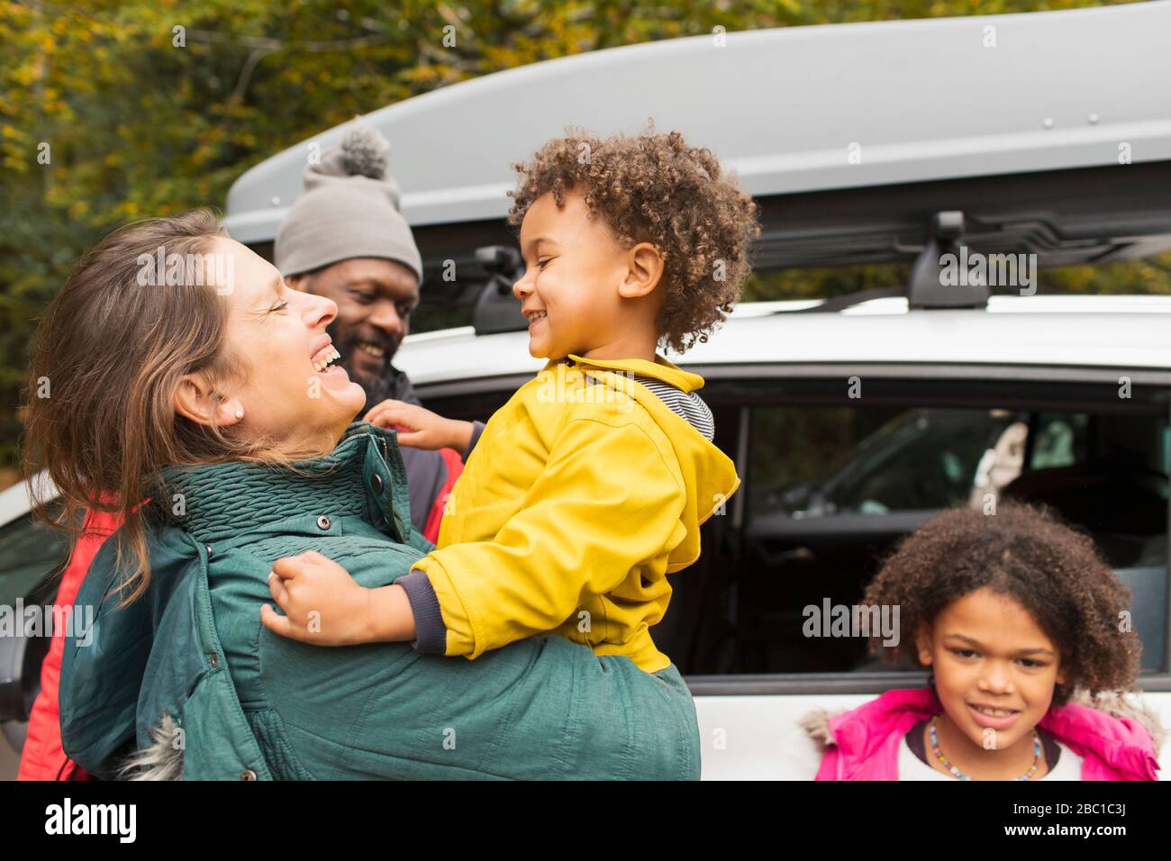 La famiglia è felice di abbracciare la macchina fuori nel parcheggio Foto Stock