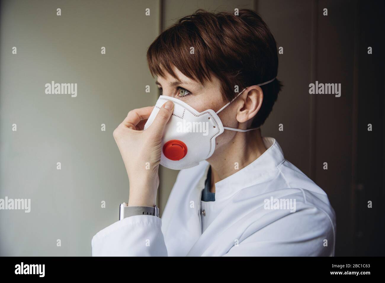 Dottore femminile che mette sulla maschera FFP3 Foto Stock
