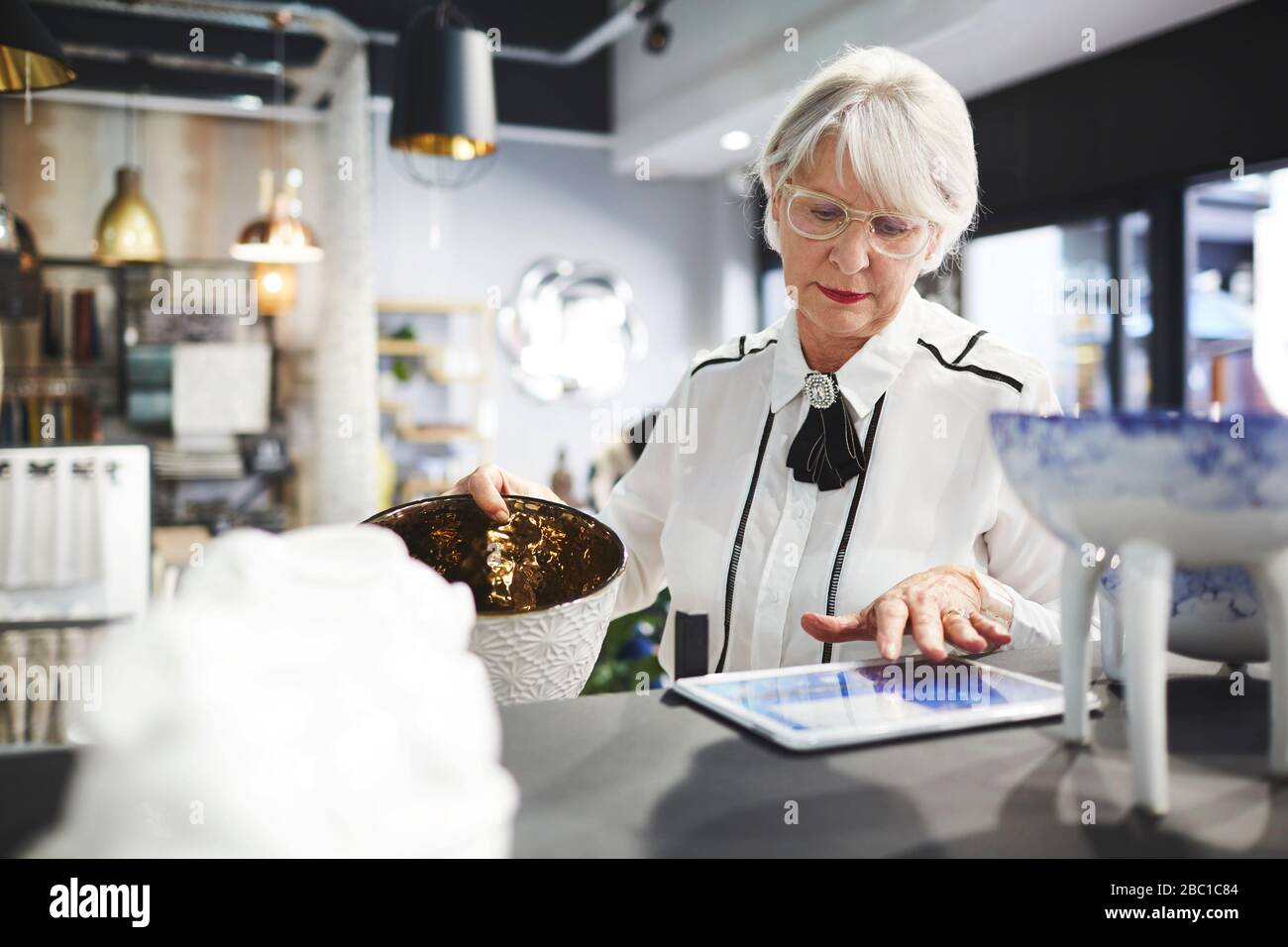 Donna anziana con acquisto di tablet digitali in negozio di articoli per la casa Foto Stock