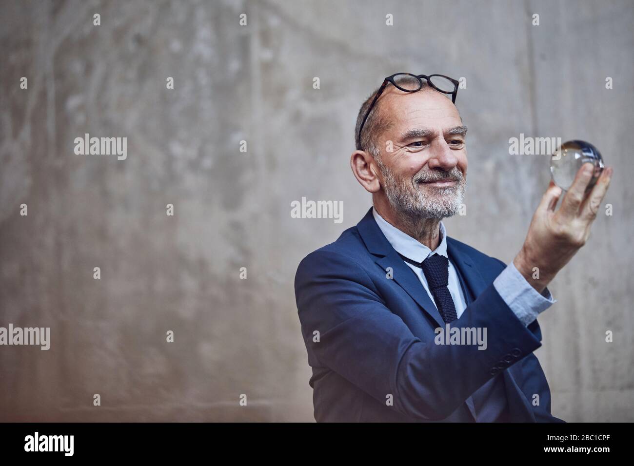 Uomo d'affari senior che guarda la palla di cristallo Foto Stock