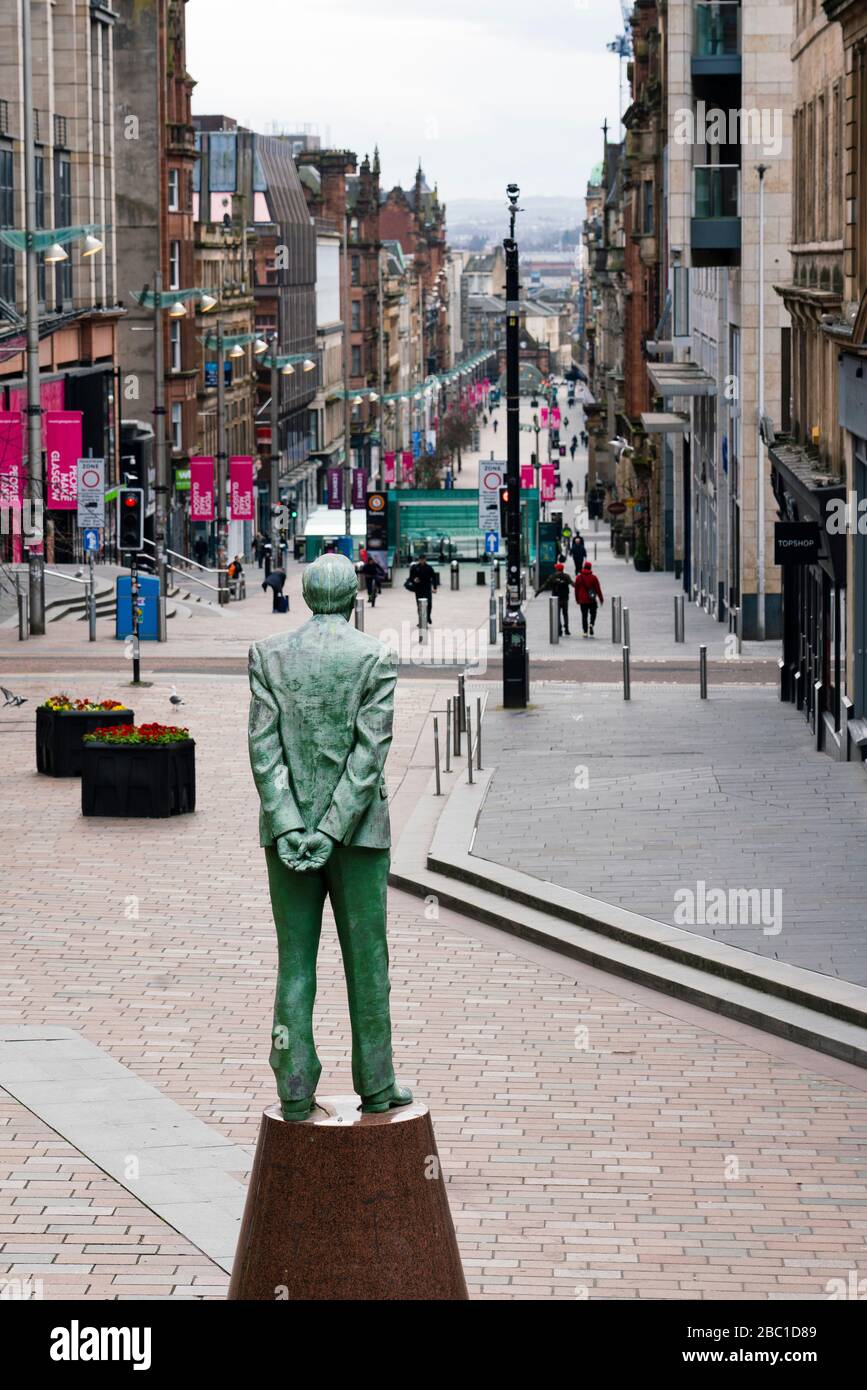 Glasgow, Scozia, Regno Unito. 1° aprile 2020. Effetti del blocco di Coronavirus sulla vita di Glasgow, Scozia. Passeggiata pubblica oltre la statua di Donald Dewar su una tranquilla B Foto Stock