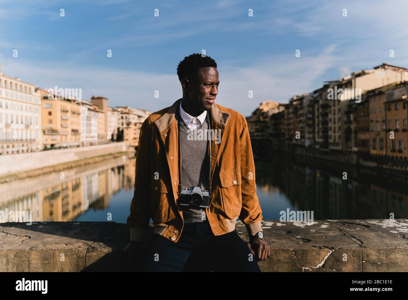 Giovane uomo con una telecamera su un ponte sopra il fiume Arno, Firenze, Italia Foto Stock