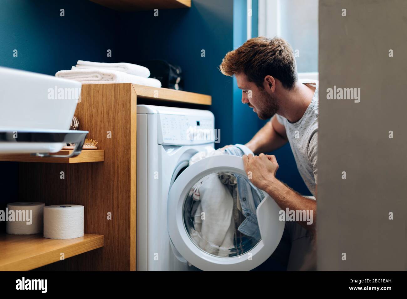 Giovane uomo che fa la lavanderia a casa Foto Stock