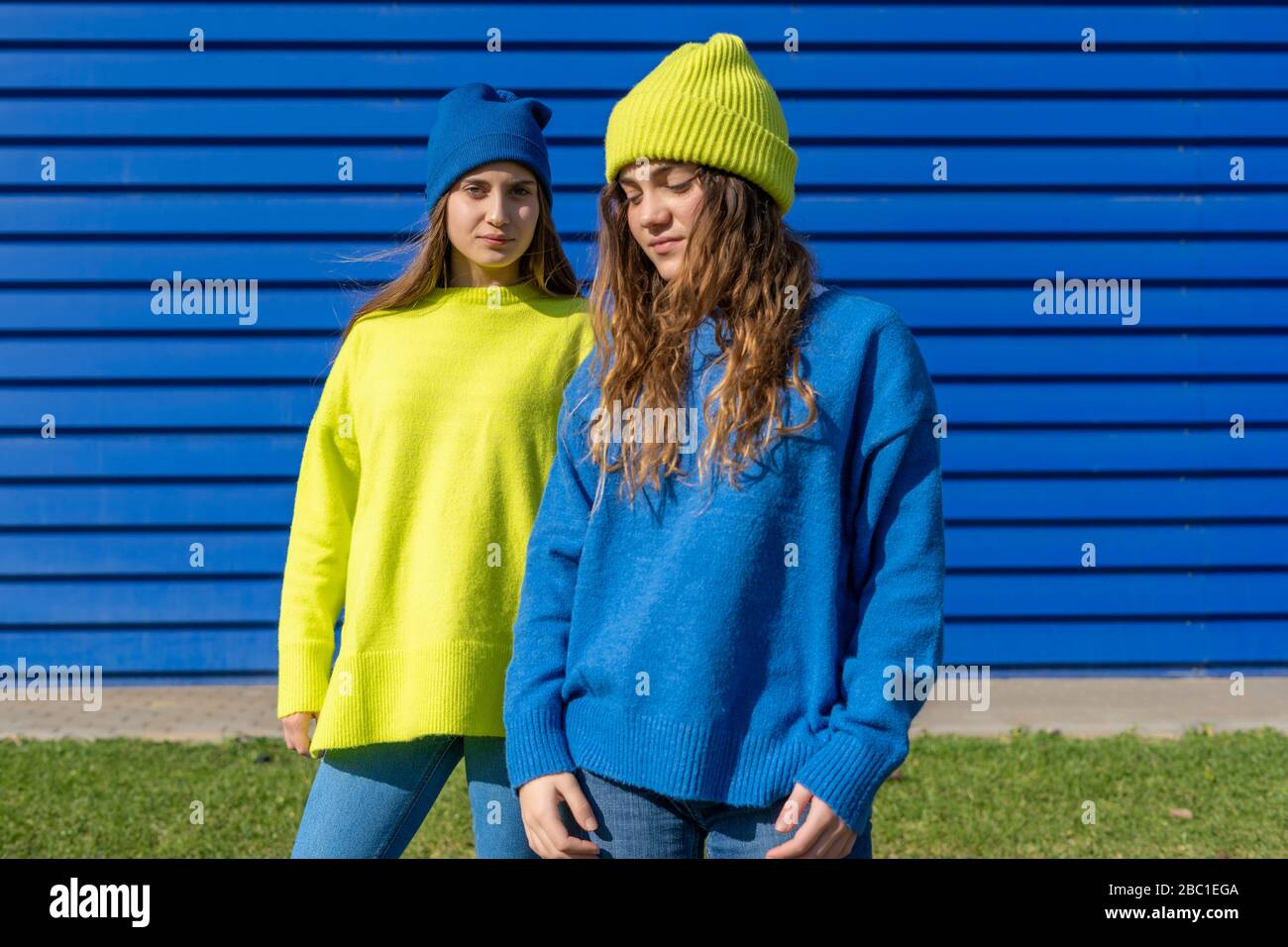 Ritratto di due ragazze adolescenti che indossano abiti corrispondenti di fronte a sfondo blu Foto Stock