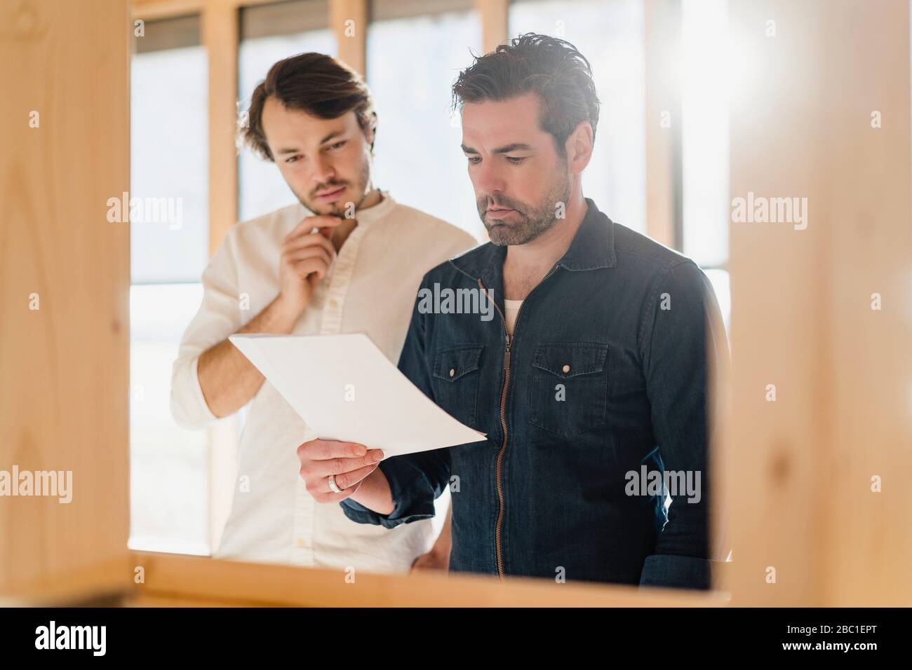 Due uomini d'affari con documento in ufficio open-plan in legno Foto Stock