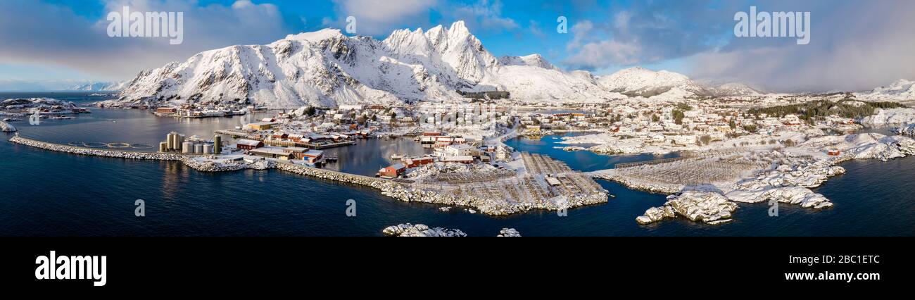 Norvegia, Ballstad, panorama aereo del villaggio di pescatori sulla riva dell'isola di Vestvagoya con montagne sullo sfondo Foto Stock