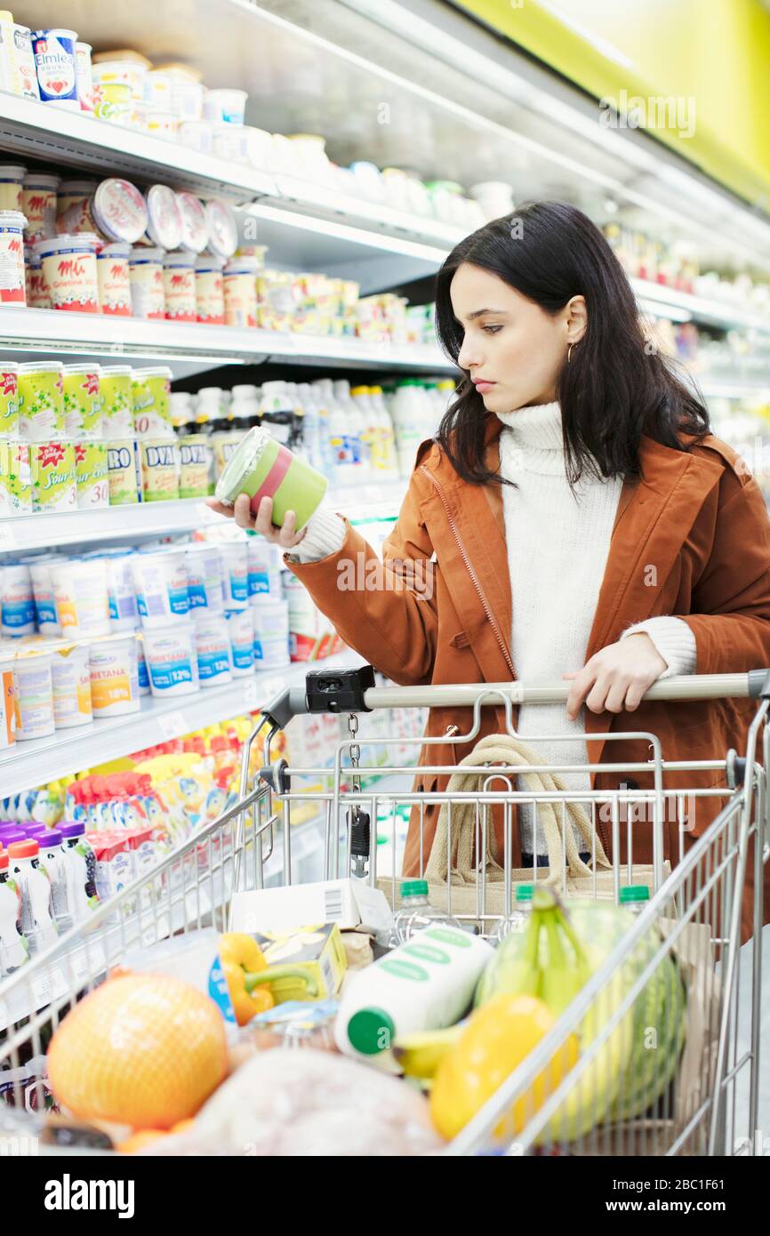 Donna che legge etichetta sul contenitore in supermercato Foto Stock