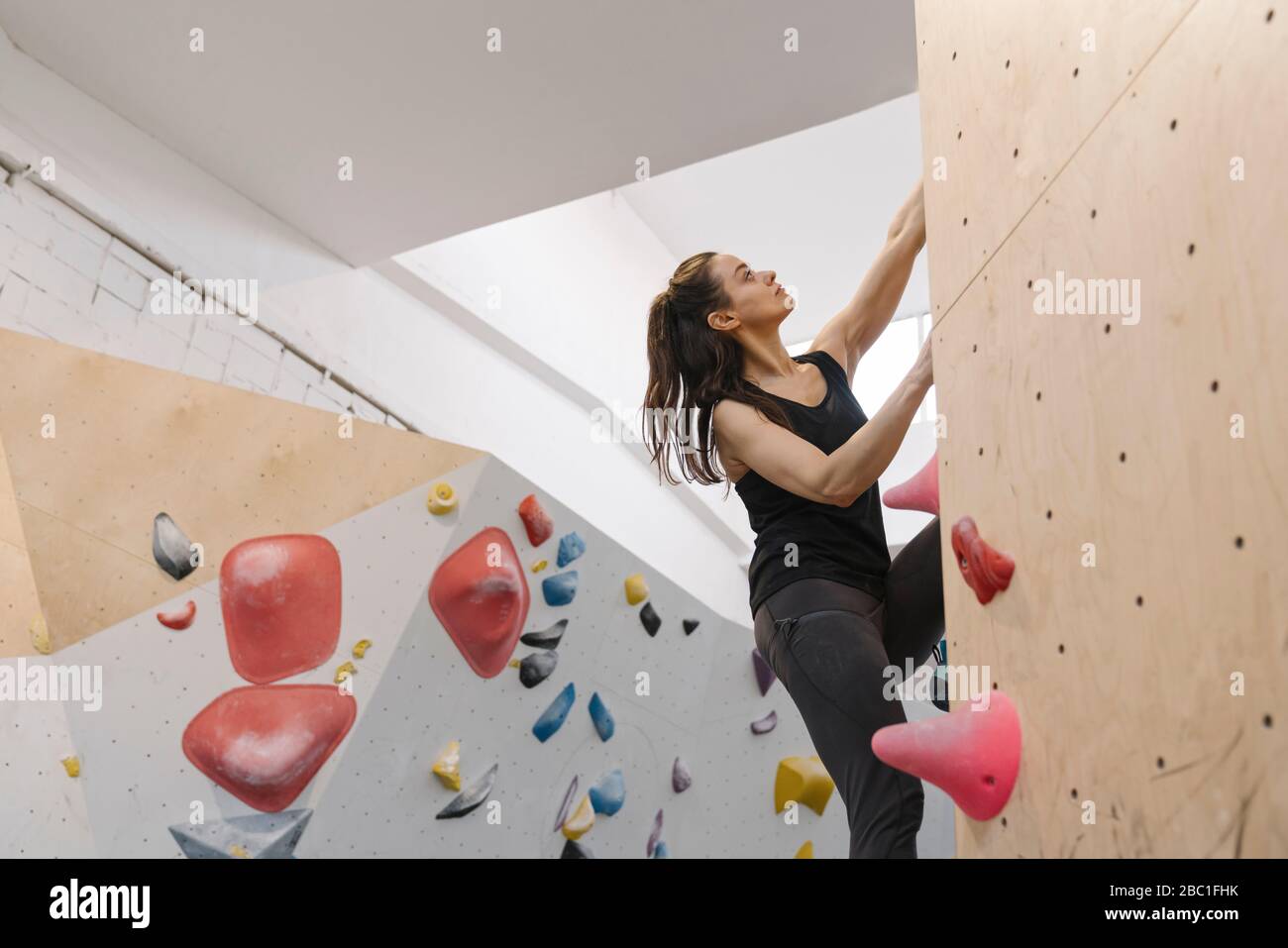 Donna bouldering in palestra di arrampicata Foto Stock