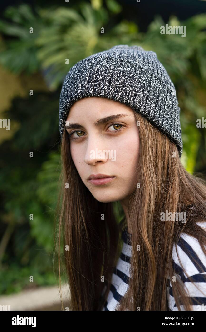 Ritratto di ragazza adolescente seria con capelli lunghi marroni che portano cappello grigio lanoso Foto Stock