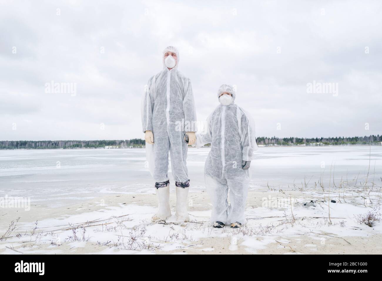 Padre e figlio indossano abiti protettivi in piedi sul fiume congelato Foto Stock