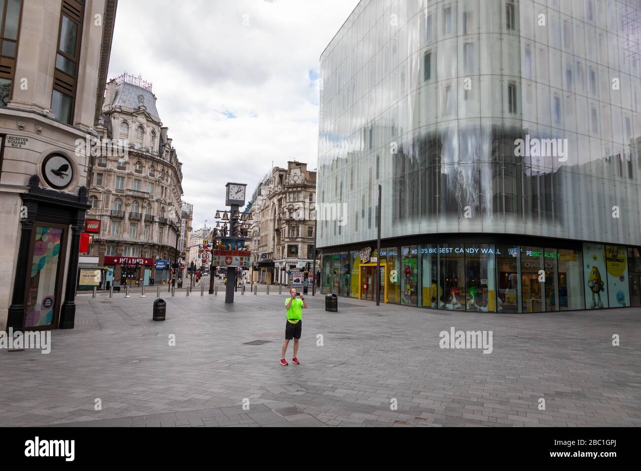 Una piazza di Leicester deserta nel centro di Londra durante l'epidemia del virus della corona. C'è un solista che ha smesso di scattare foto. Foto Stock