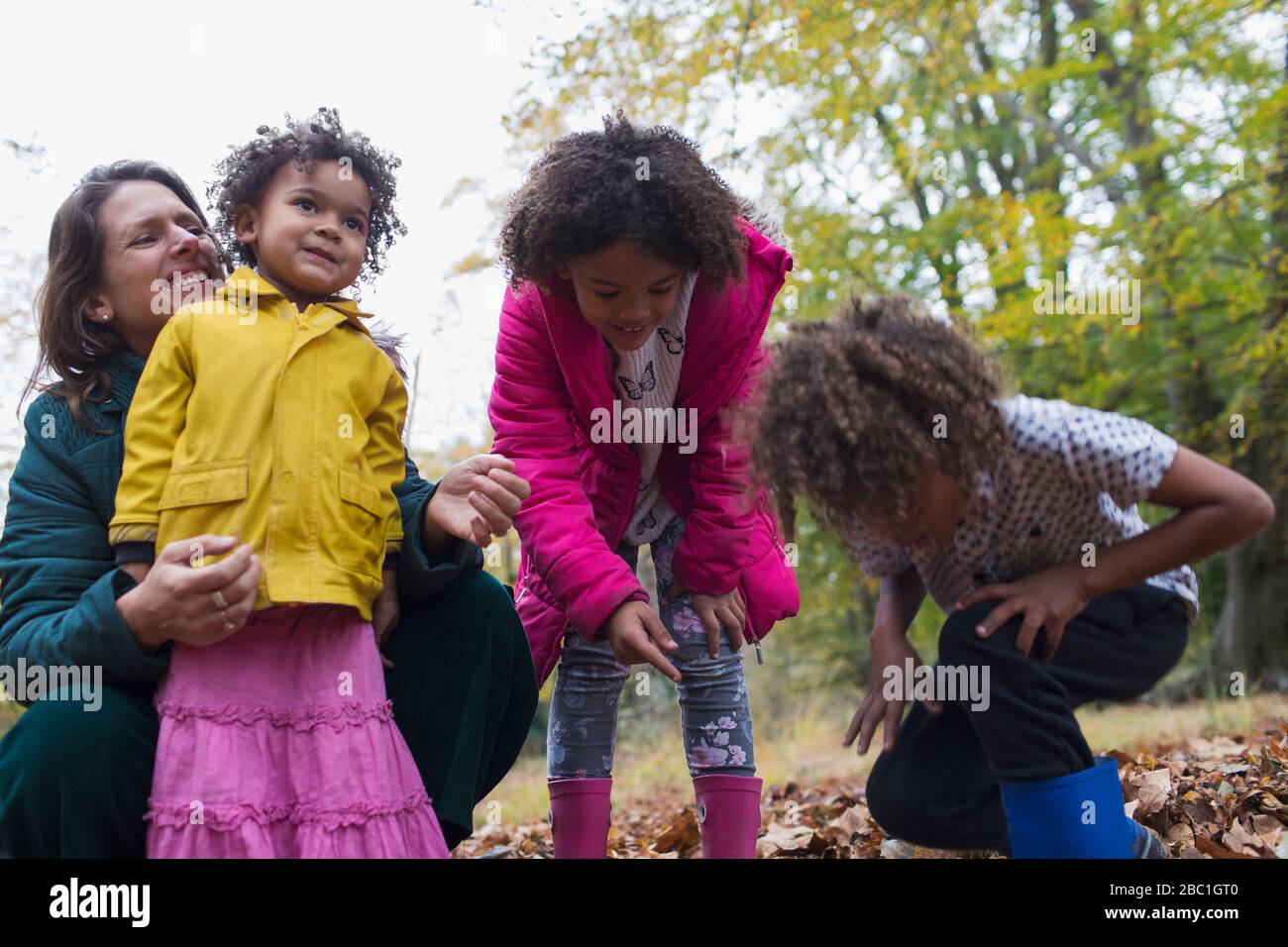 Madre felice e bambini che giocano in autunno lascia Foto Stock