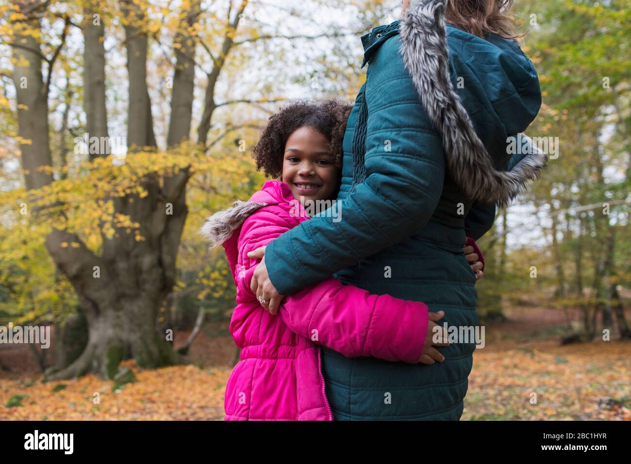 Ritratto di ragazza felice che abbrana madre in autunno boschi Foto Stock