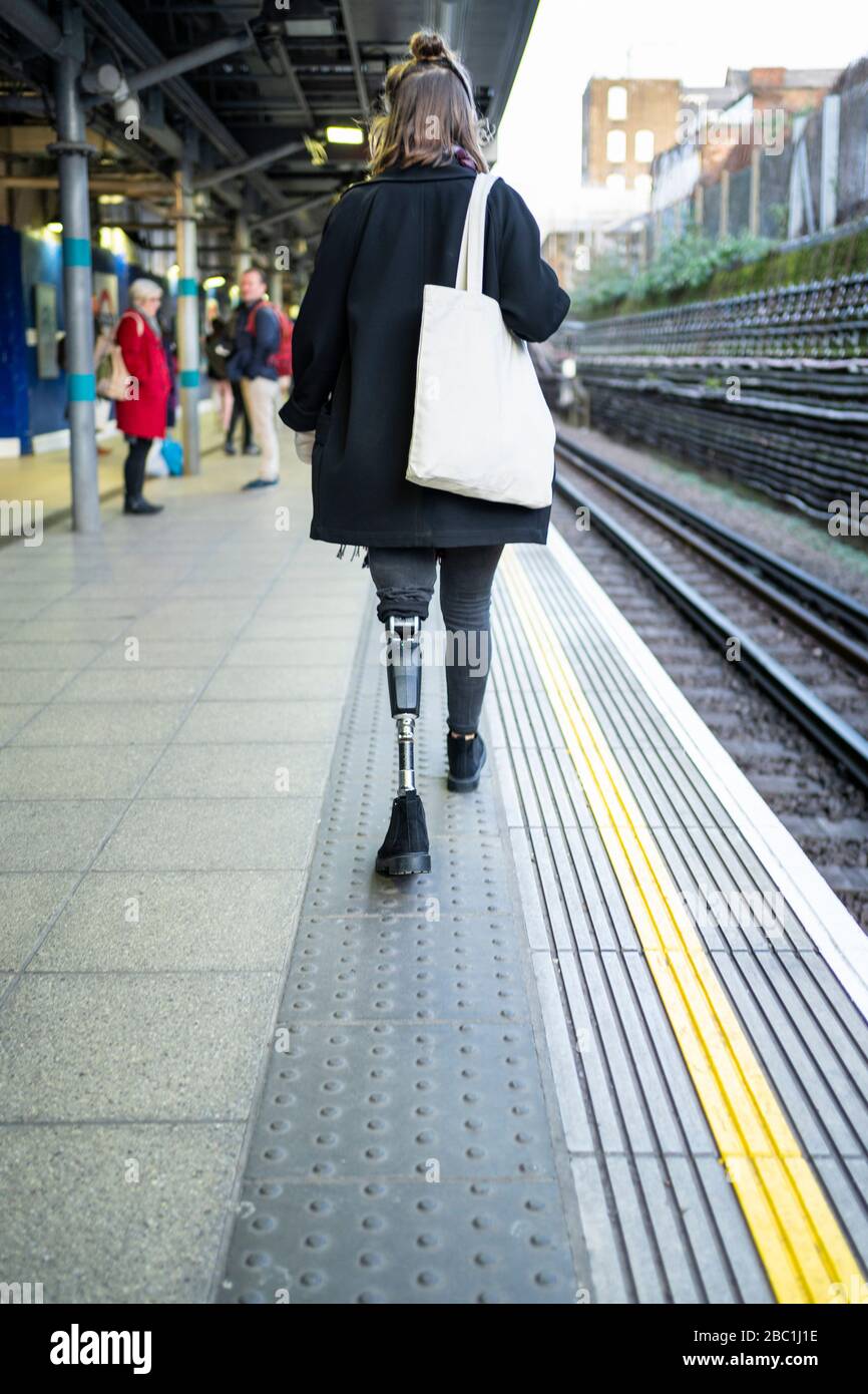 Vista posteriore della giovane donna con protesi delle gambe che cammina al  plafom della stazione Foto stock - Alamy