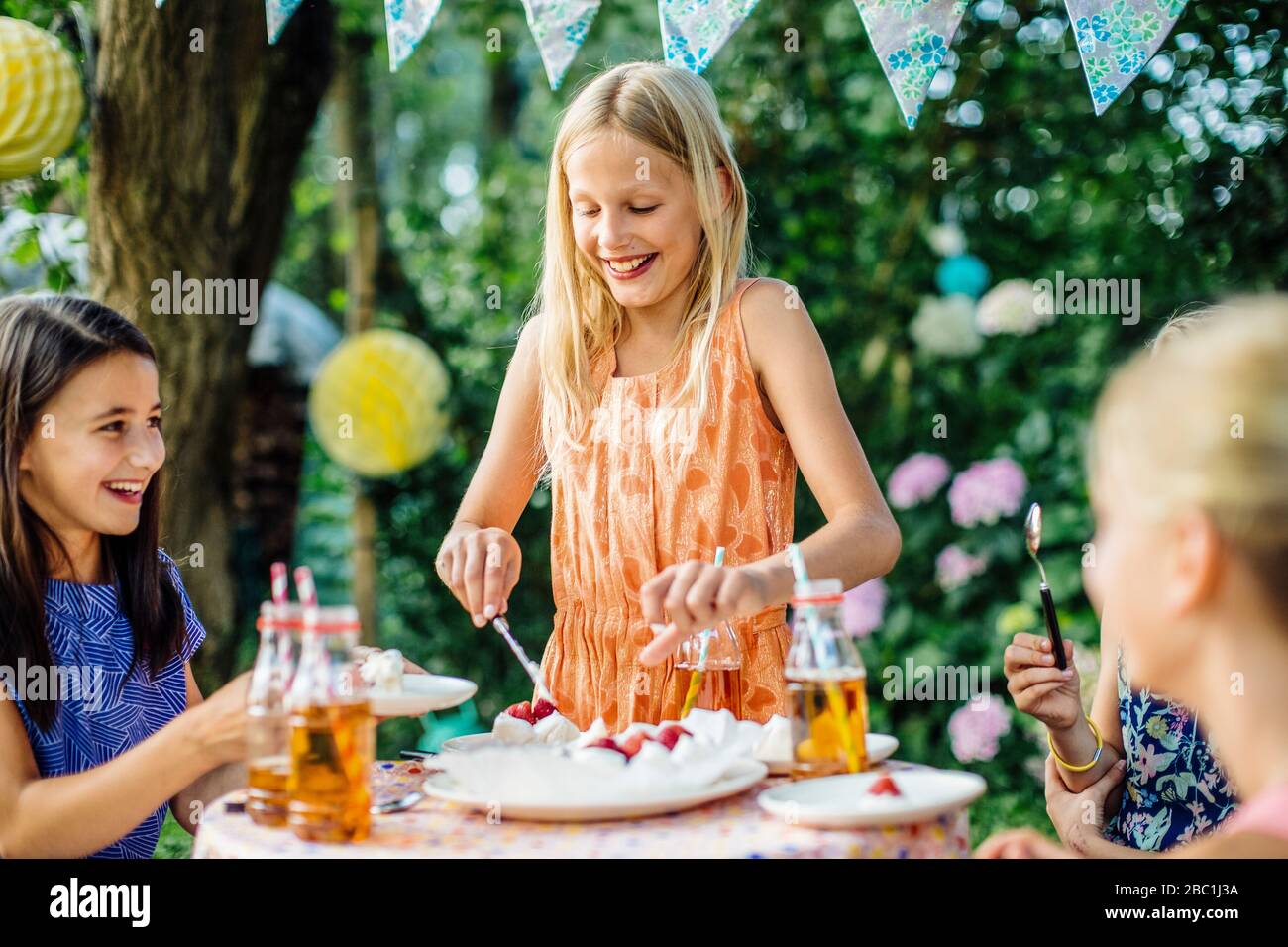Ragazza che si tuffa in torta su una festa di compleanno all'aperto Foto Stock