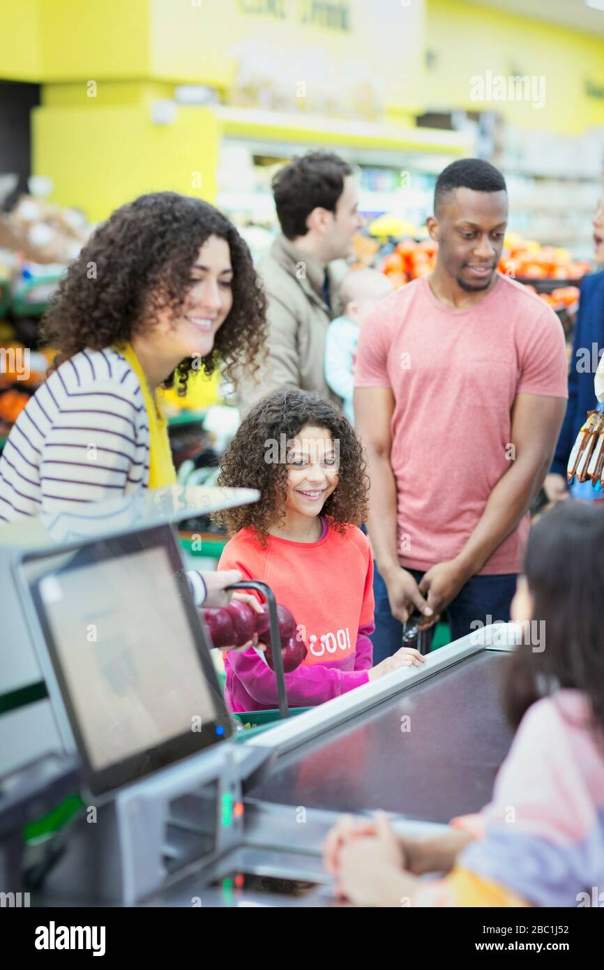 Cassiere che aiuta madre e figlia al checkout supermercato Foto Stock