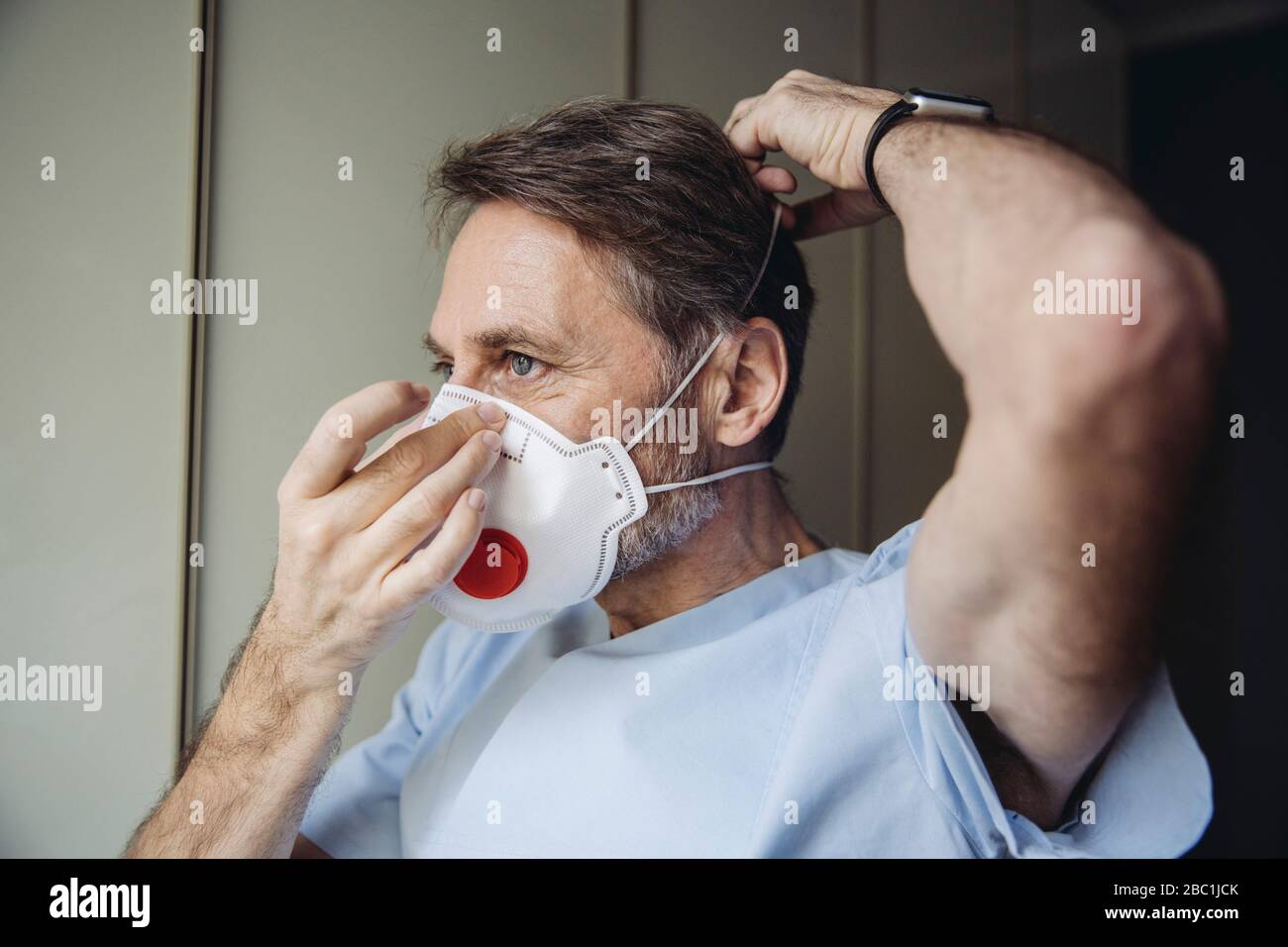 Operatore sanitario maschile che mette su maschera FFP3 Foto Stock