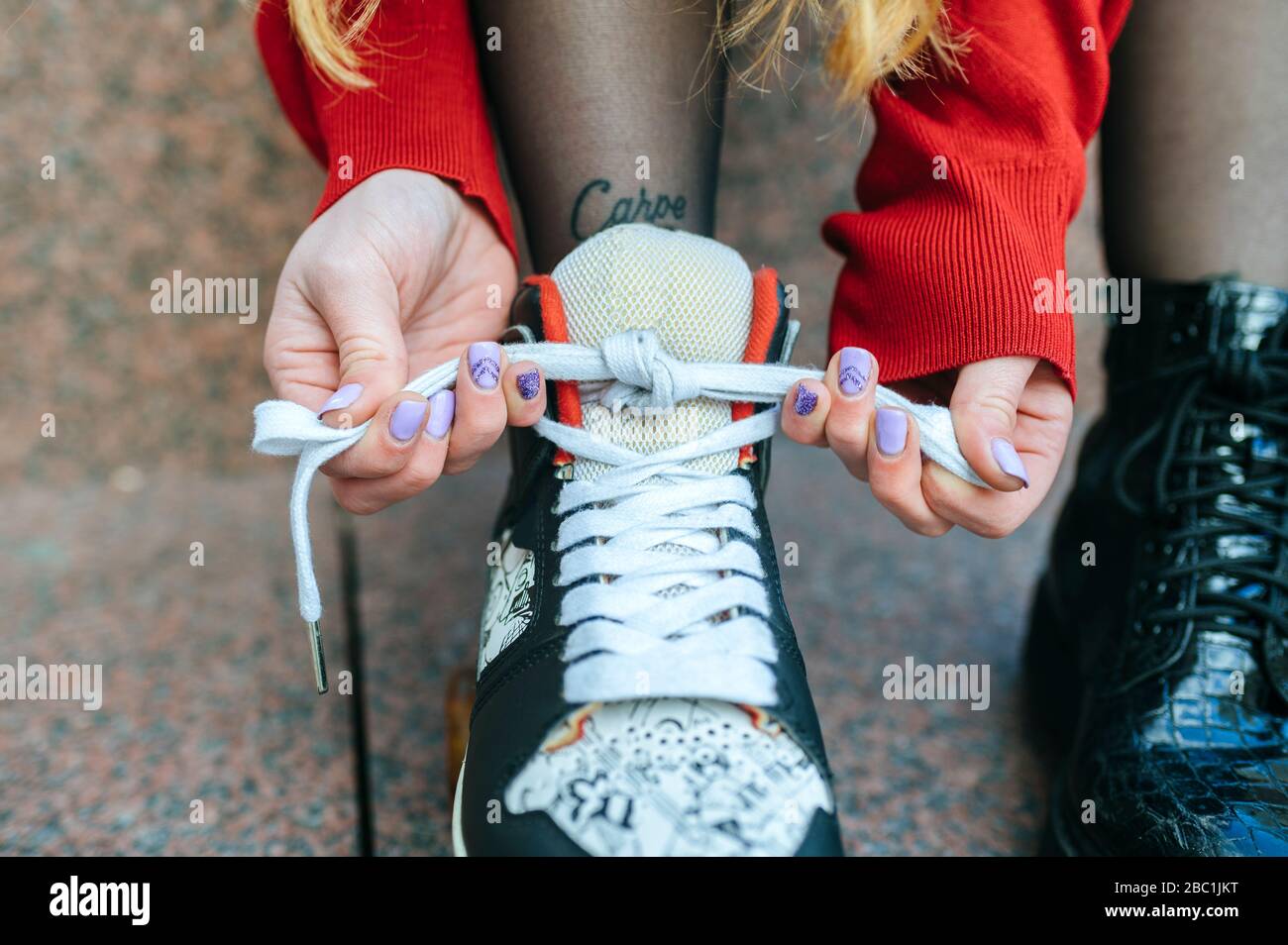 Primo piano di una giovane donna che mette su pattini a rotelle Foto Stock
