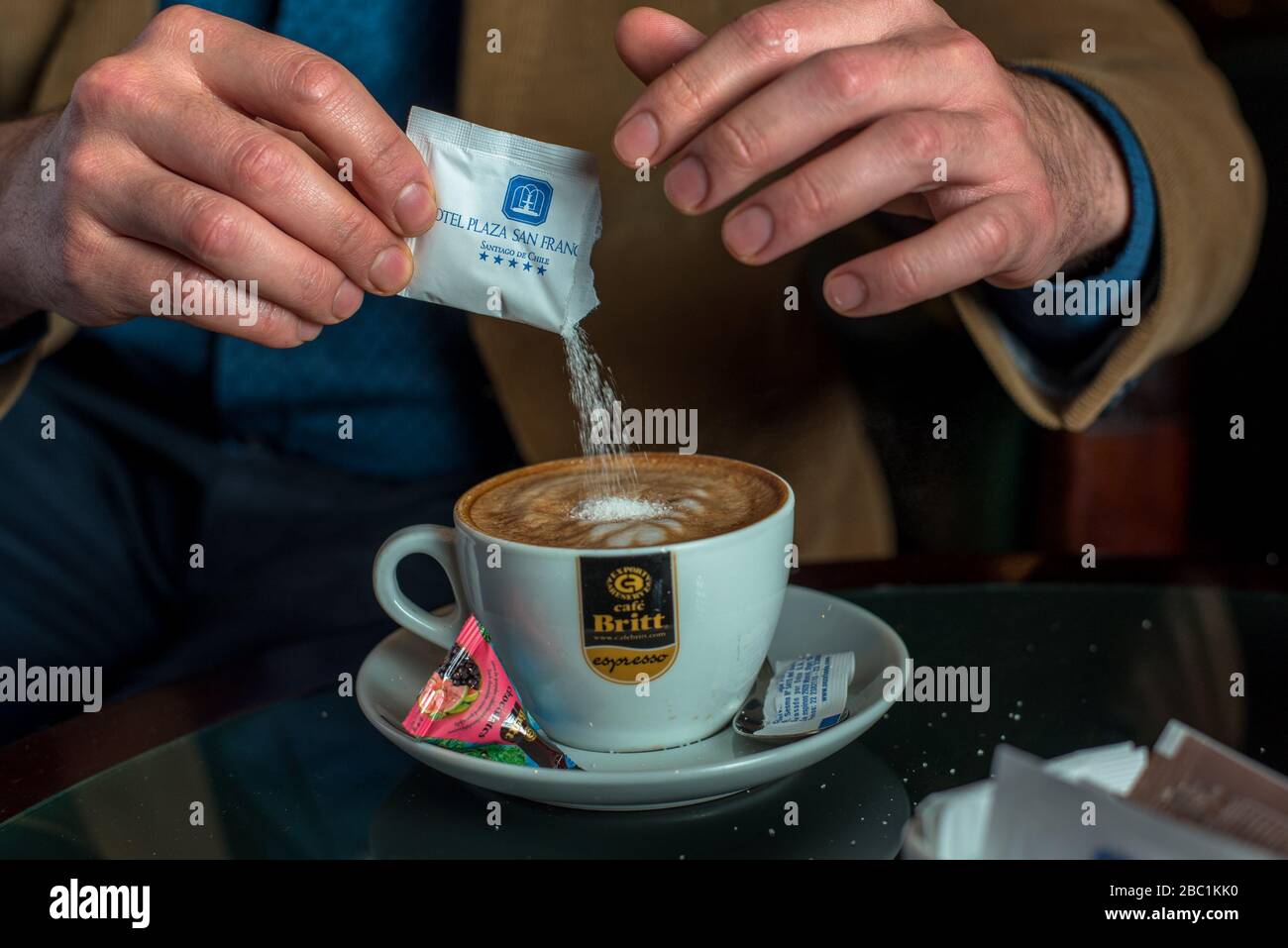 Uomo che serve lo zucchero al suo caffè Foto Stock