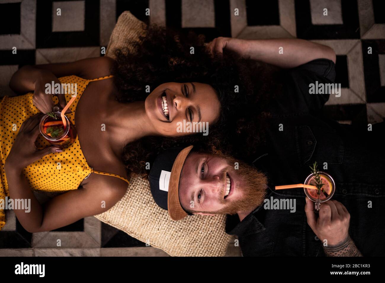 Ritratto di coppia felice sdraiato sul pavimento bere fresco tè di ghiaccio Foto Stock