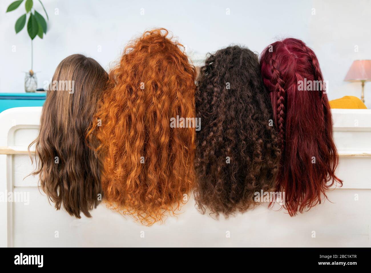 Vista posteriore di quattro donne con lunghi capelli castani e rossi Foto Stock