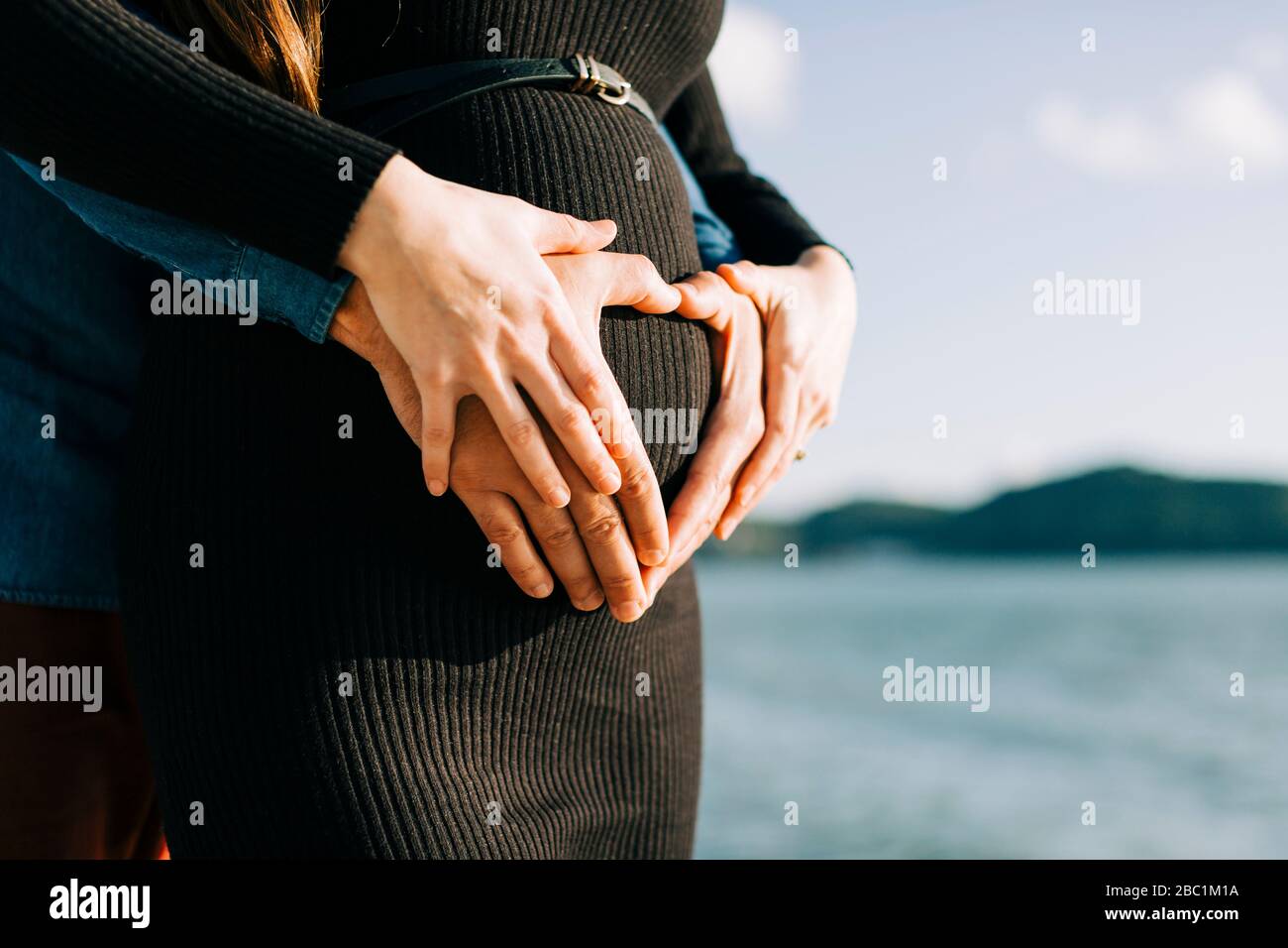 Affettuoso genitori in attesa che modellano un cuore con le loro mani sul ventre del bambino Foto Stock