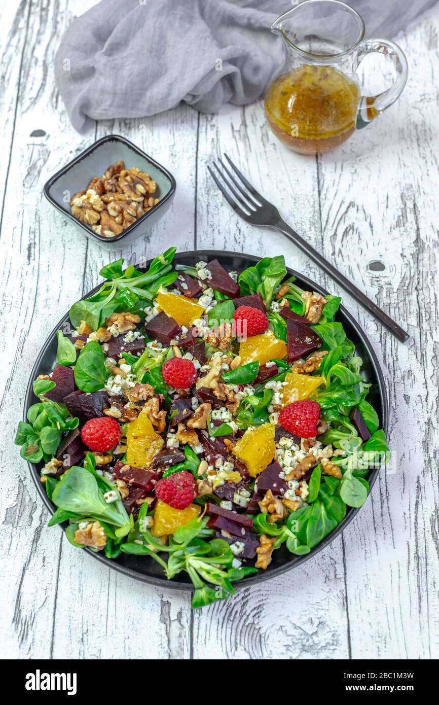 Piatto di insalata mista colorata con formaggio feta, barbabietola comune, noci, pinoli, lamponi, arance e insalata di mais Foto Stock