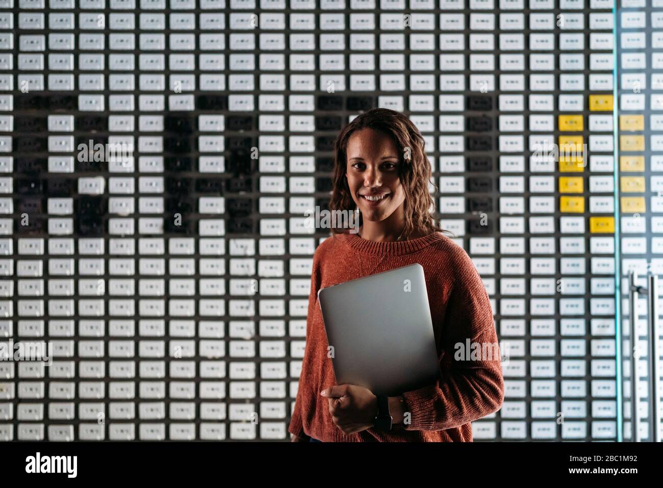 Ritratto di una giovane donna che tiene il laptop a parete con la parola "radio" Foto Stock