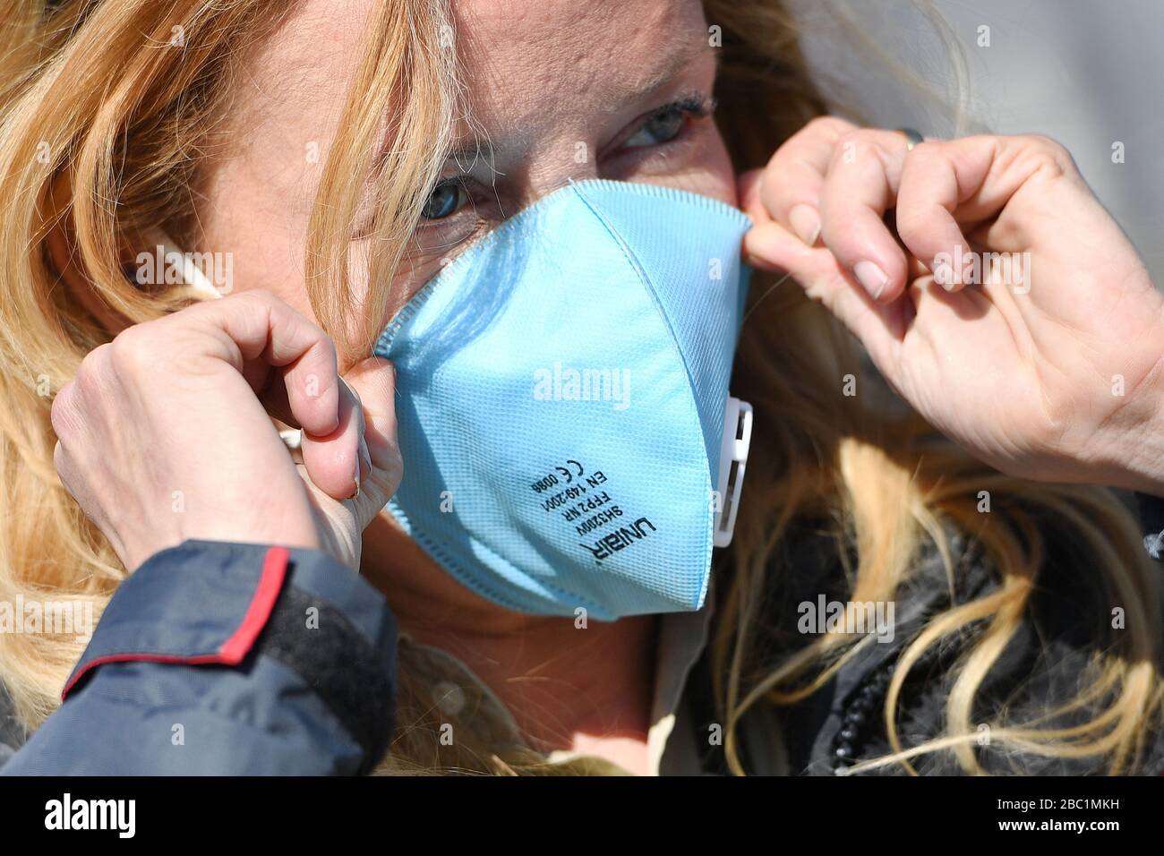 Monaco, Germania. 02nd Apr, 2020. Una donna mette una maschera facciale FFP2 sul suo viso. Maschera, maschera protettiva, maschera facciale, protezione antivirus, troppe infezioni da corona: Muenchner Helios Klinik cede le operazioni quotidiane. A causa di un gran numero di infezioni da corona tra pazienti e dipendenti, il Muenchner Klinik cede temporaneamente le normali operazioni ospedaliere. Anche la sala d'emergenza è interessata. Le catene di infezione sono da rompere il 2nd aprile 2020 | utilizzo in tutto il mondo credito: dpa/Alamy Live News Foto Stock
