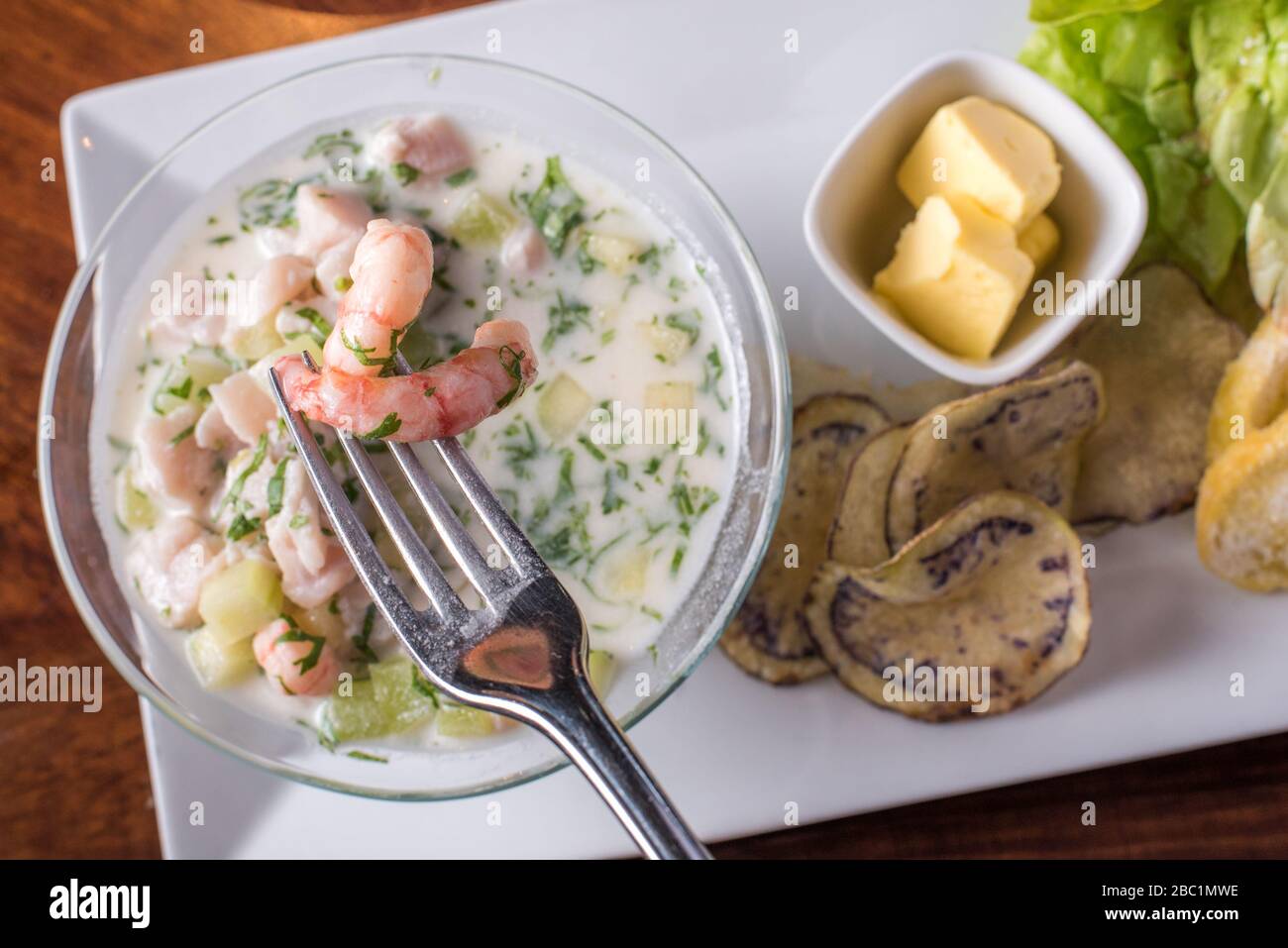 uomo che gode di un ceviche con patatine, insalata e pisco Foto Stock