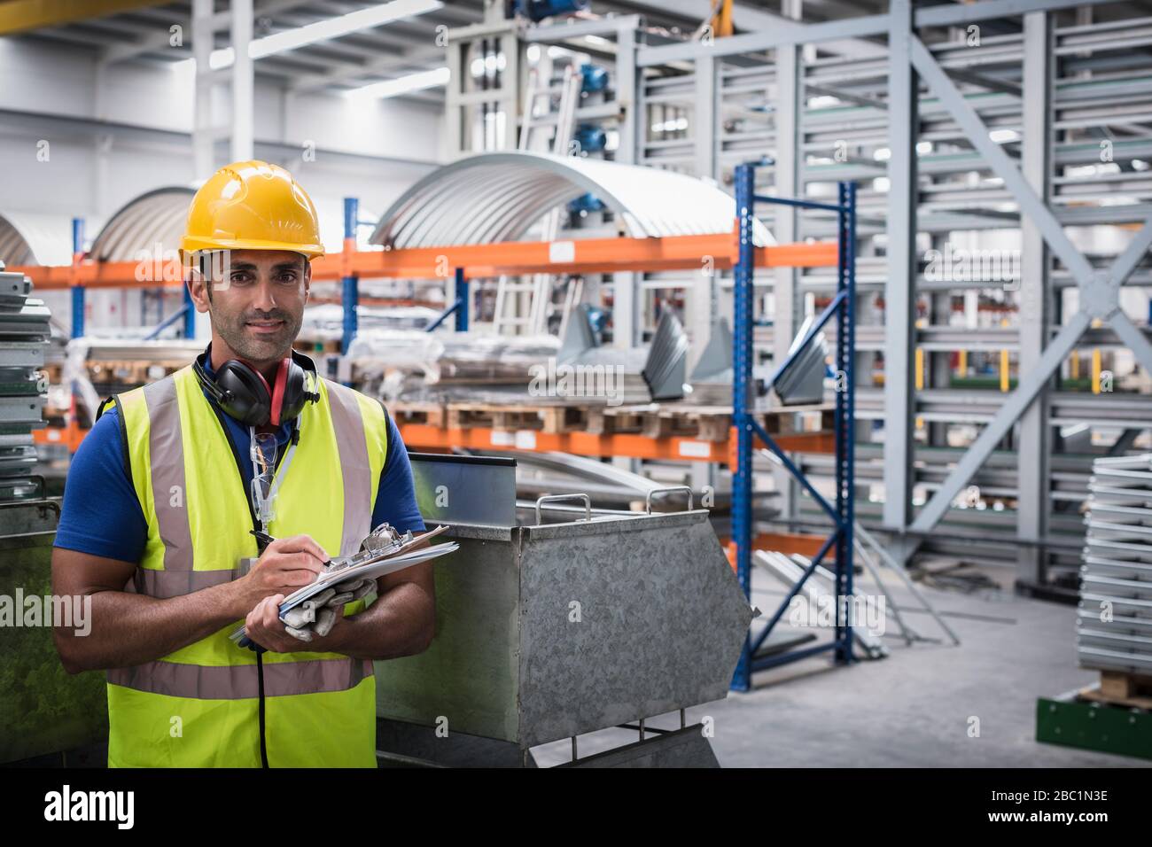 Supervisore maschile sicuro di ritratto con appunti in fabbrica d'acciaio Foto Stock