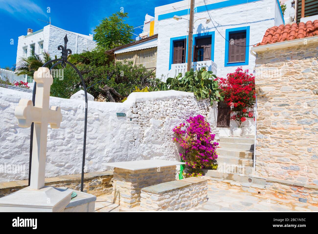 Vista sulla strada di Ano Syros con alberi di bougainvillea colorati e case tradizionali sull'isola di Syros, Grecia Foto Stock