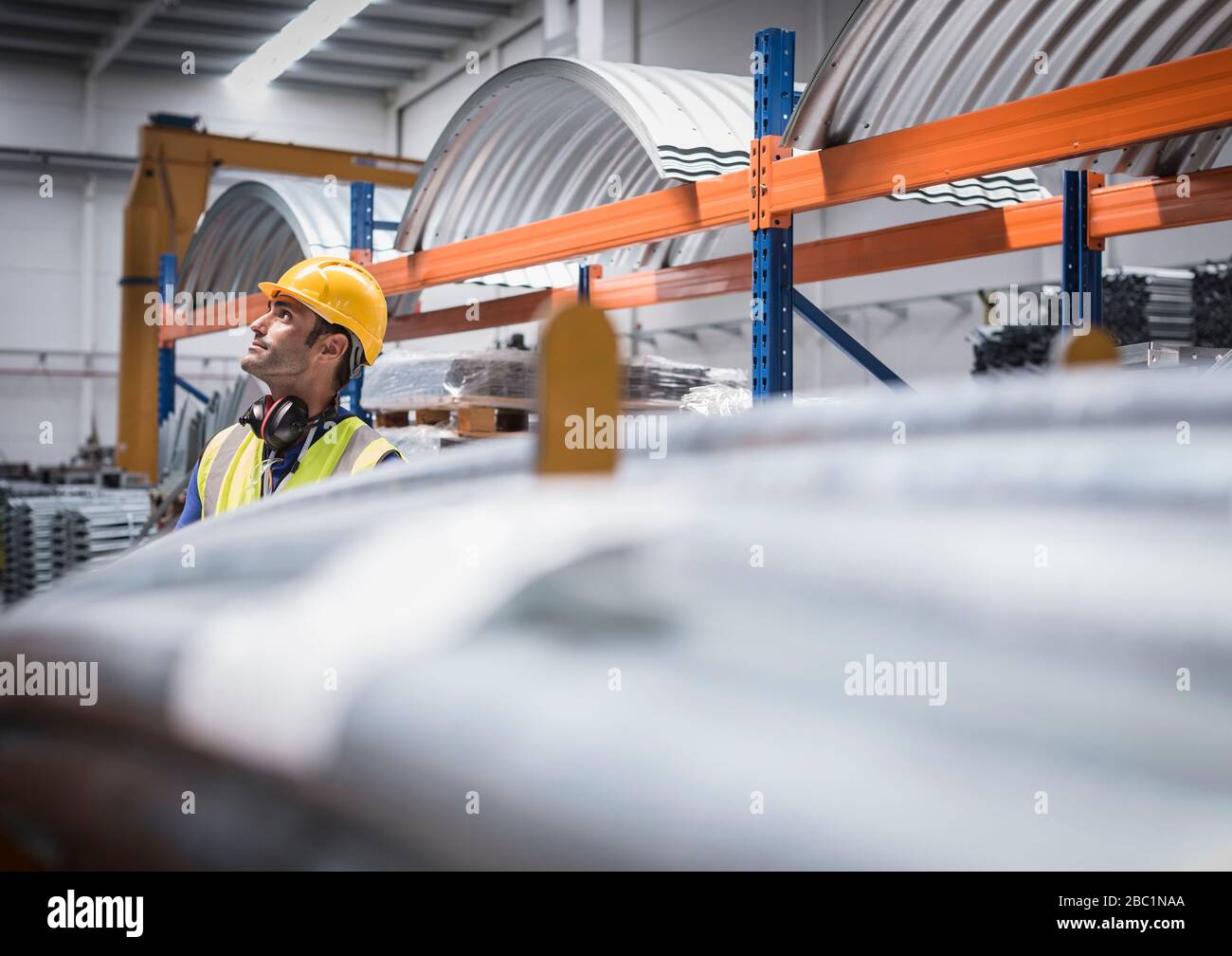 Lavoratore maschile che guarda in su in fabbrica di acciaio Foto Stock