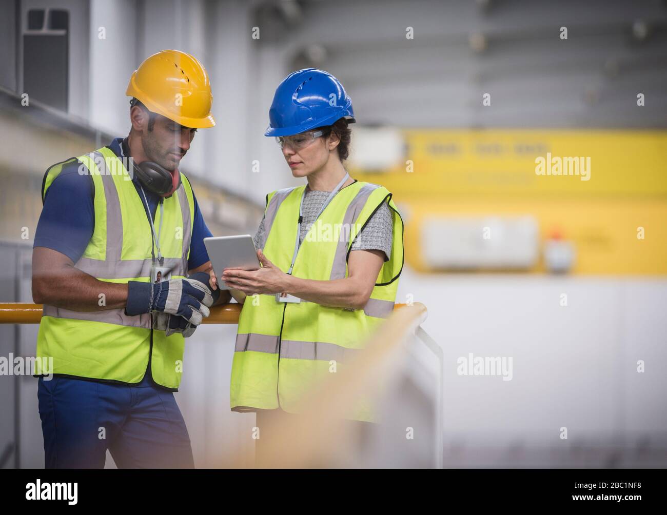 Supervisori con tablet digitali che parlano su piattaforma in fabbrica Foto Stock