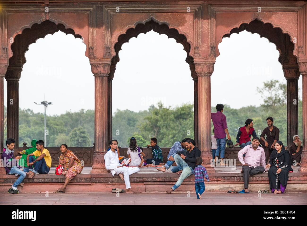 La gente del posto si rilassa sotto gli archi architettonici alla moschea di Jama Masjid nella Vecchia Delhi, India Foto Stock