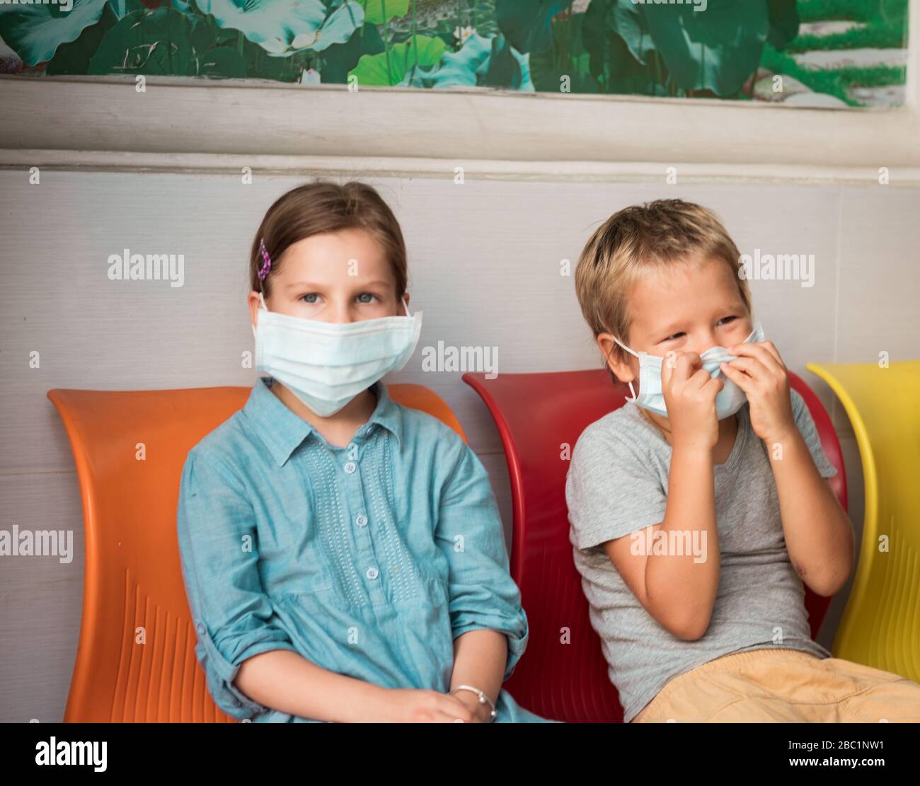 Bambini che indossano una maschera facciale monouso per evitare infezioni virali. Protezione antivirus Foto Stock