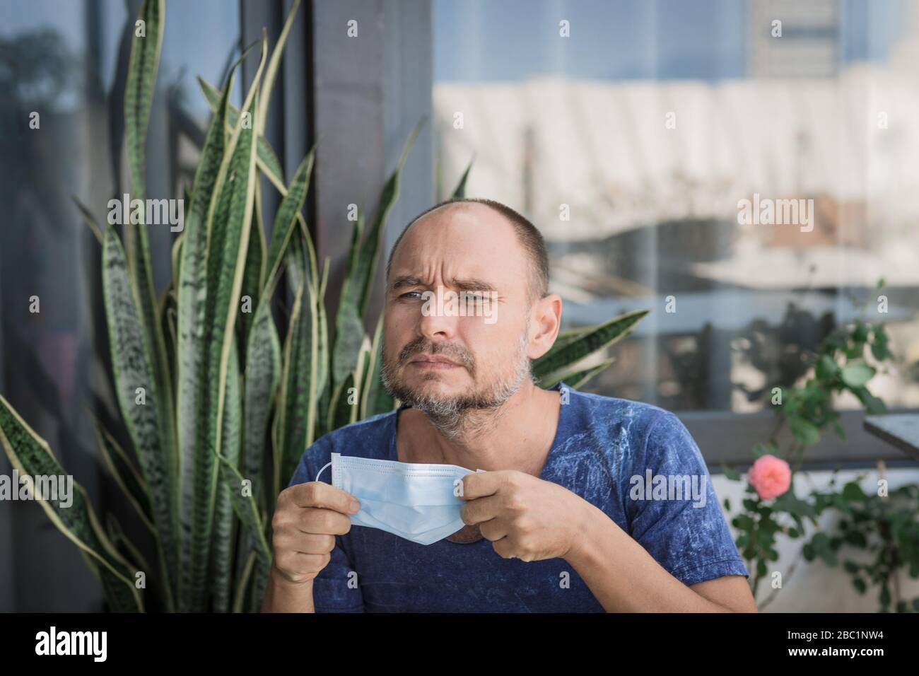 Uomo che indossa una maschera facciale monouso per evitare infezioni virali. Protezione antivirus Foto Stock