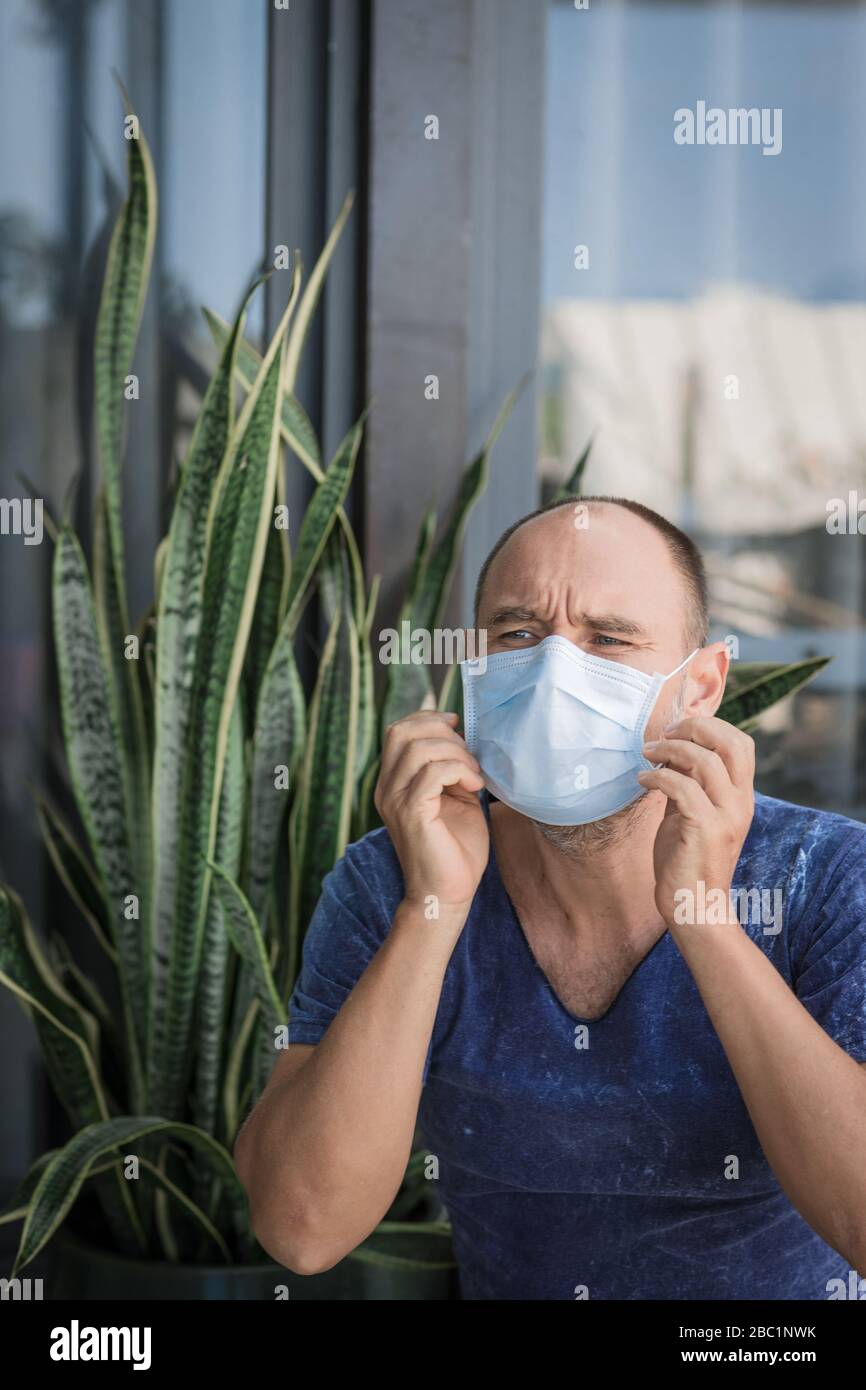 Uomo che indossa una maschera facciale monouso per evitare infezioni virali. Protezione antivirus Foto Stock